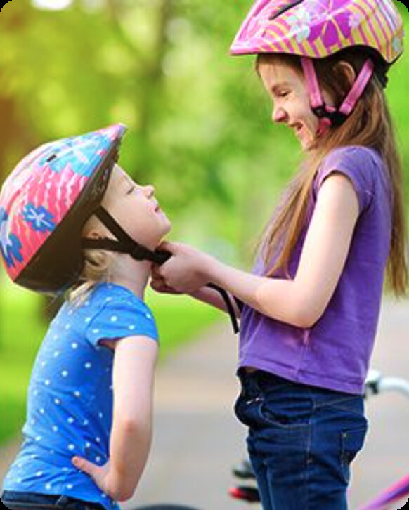 Child helping adjust another child's helmet